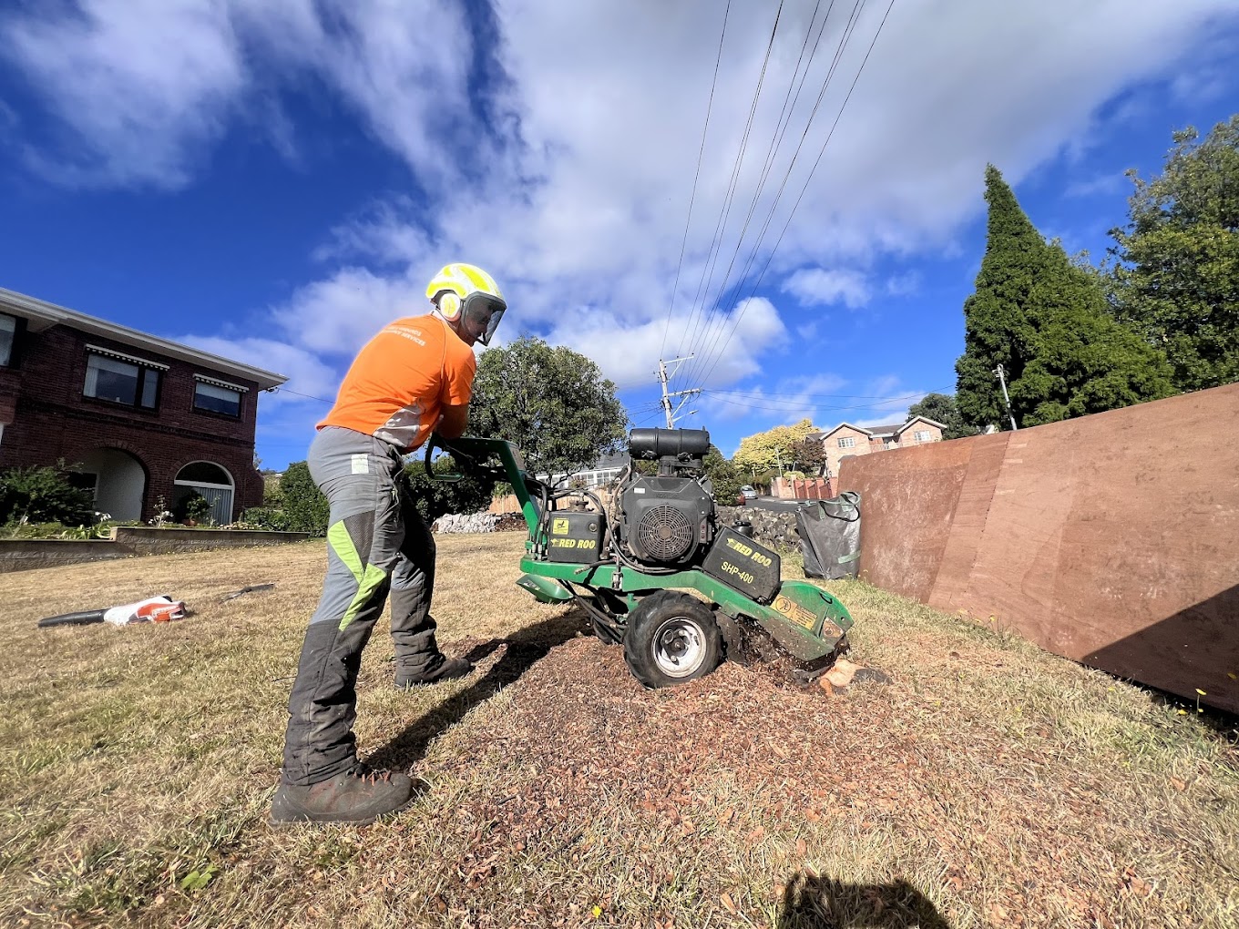 Man removing tree stump with a stump grinding machine.